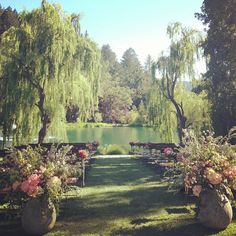 an outdoor ceremony setup with flowers and benches in the foreground, surrounded by trees