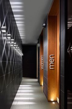 an empty hallway with black walls and wooden signs on the wall, along with floor to ceiling lighting