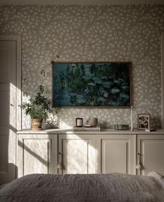 a bed sitting under a painting on top of a wall next to a white dresser