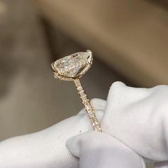 a close up of a person's hand holding a ring with a pear shaped diamond on it