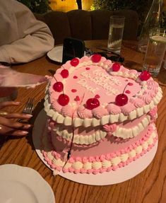 a pink heart shaped cake sitting on top of a table next to plates and silverware