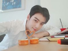 a young man sitting at a table with some orange glasses on top of his head