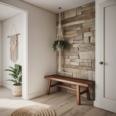 a wooden bench sitting in front of a stone wall next to a potted plant