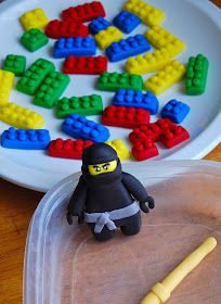 a lego man is standing in front of a plate with colored blocks and a stick