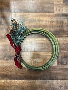 a wreath on the floor with flowers and ribbons tied around it, ready to be used as an ornament