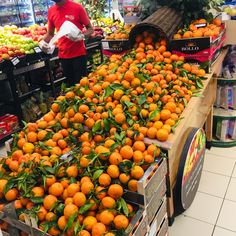 an orange stand in a grocery store filled with lots of oranges and other fruit