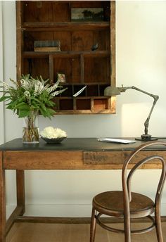 a wooden desk with a lamp and flowers on it