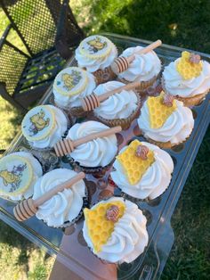 cupcakes with white frosting and honey combs on top are sitting in a plastic container