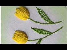 two yellow tulips with green leaves on a white cloth background, one has been stitched to the side