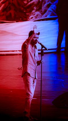 a man standing in front of a microphone on top of a red and blue stage