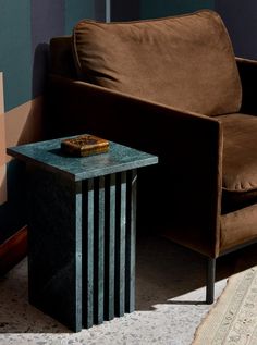 a brown couch sitting next to a wooden table on top of a carpeted floor