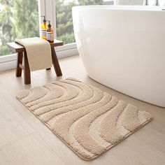 a white bath tub sitting next to a wooden stool in a bathroom under a window