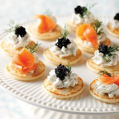 small appetizers with cream cheese and salmon on them are arranged on a white platter