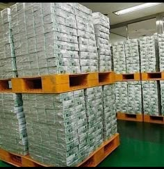 stacks of money are stacked on pallets in a large room with green flooring