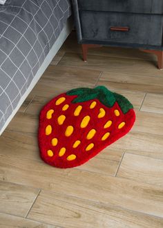 a strawberry shaped rug on the floor next to a bed