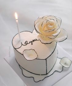 a small white cake with a candle in the shape of a heart