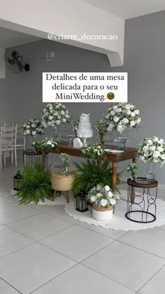 a table with white flowers and greenery on it in front of a sign that says,