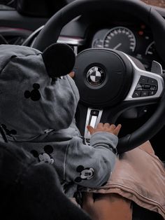 a baby is sitting in the driver's seat of a car and playing with a steering wheel