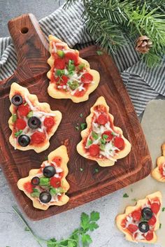 mini pizzas with olives, tomatoes and cheese on a cutting board