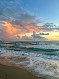 the sun is setting over the ocean with waves crashing on the shore and clouds in the sky