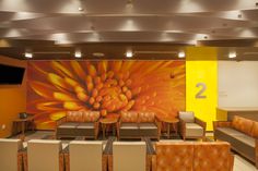 an empty waiting room with couches and chairs in front of a large flower painting