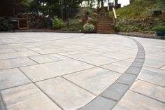 an empty patio with steps and plants in the background