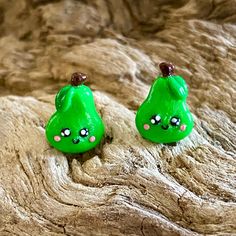 two green earrings sitting on top of a piece of drifty wood next to each other