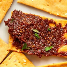 some crackers are topped with chili sauce and sprinkled with parsley on top