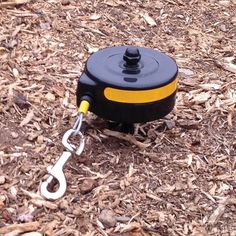 a black and yellow pulley is sitting on the ground with a chain attached to it