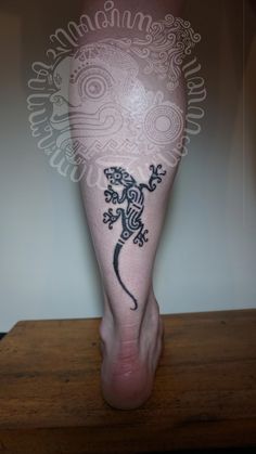 a lizard tattoo on the leg of a person's foot with an intricate design