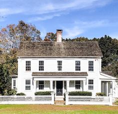 a large white house sitting on top of a lush green field