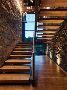 the stairs are made of wood and have lights hanging from them above them, along with stone walls