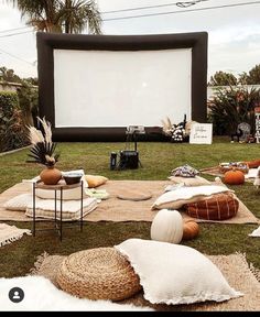 an outdoor movie is set up on the grass in front of a large screen and chairs