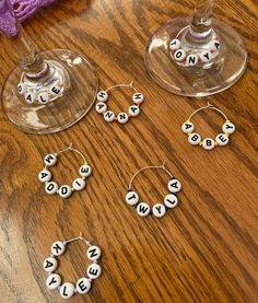 three wine glasses and two wine charms on a wooden table with the word wine spelled in small letters