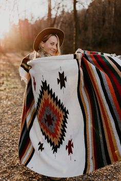 a woman is holding up a blanket in the woods