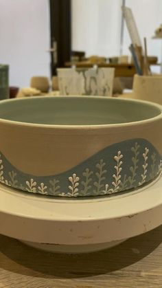 a bowl sitting on top of a wooden table next to other bowls and pottery items