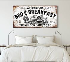 a bed with white sheets and pillows in front of a sign that reads welcome to bed & breakfast