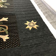 a close up of a black quilt with gold stars on it and another patchwork design