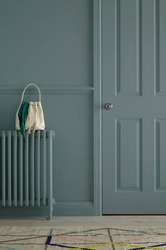 a radiator in front of a green door with a purse hanging on it