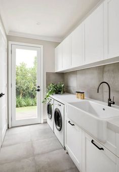 a washer and dryer in a white laundry room with doors leading to the outside