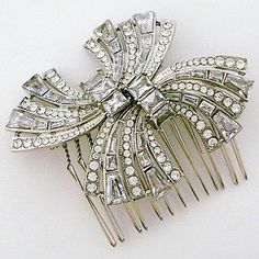 a silver hair comb with crystal stones on the top and sides, sitting on a white surface