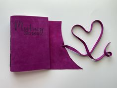 a purple book with writing on it next to a heart shaped ribbon that says wedding notes