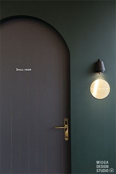 an open door to a green room with a lamp on the wall next to it