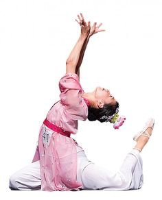 a woman in pink shirt and white pants on the ground with her arms up above her head