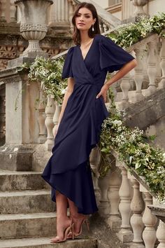 a woman in a blue dress standing on some stairs