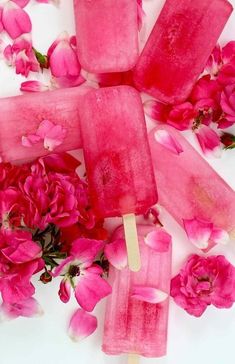 popsicles with pink flowers and petals on a white surface