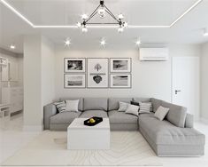 a white living room with grey couches and pictures on the wall