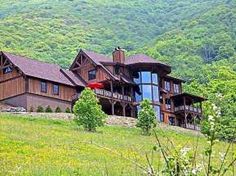 a large wooden house sitting on top of a lush green hillside