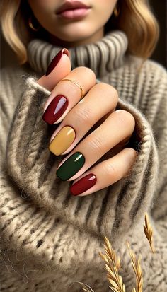 Hand with October-inspired nails in burgundy, mustard yellow, and green with minimalist gold accents on a neutral background. Fall Yellow Nails Design, Green And Mustard Nails, Nail Autumn 2024, Warm Autumn Nails, Thanksgiving Color Nails, Short Dip Nails Fall, Nails Green And Yellow, Nails Autumn 2024, Yellow Autumn Nails