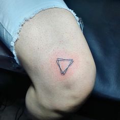 a small triangle tattoo on the back of a woman's thigh